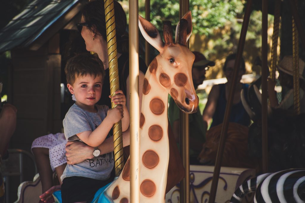 Kind und Erzieherin im Karussell während eines Kindergartenausfluges.